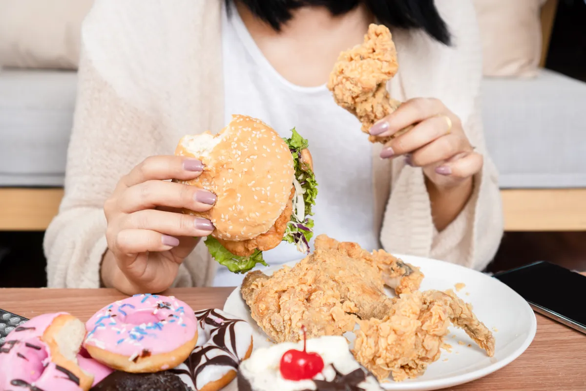 Woman eating burger and fried chicken