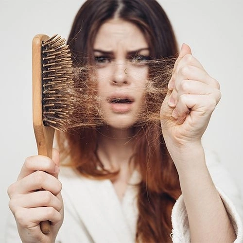 Lady with hair comb showing hair loss | Boost Wellness Clinic | Missouri City, TX